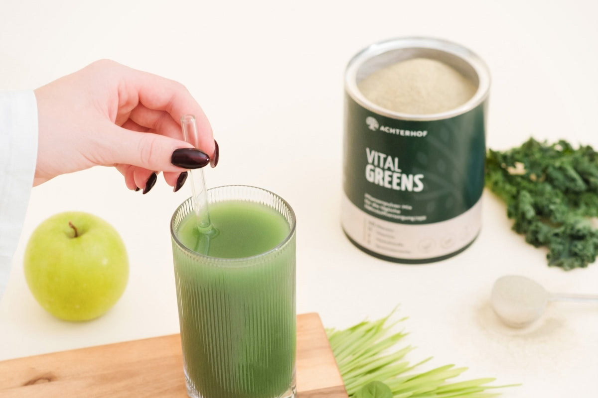 Vital Greens wird in ein Glas Wasser gegeben